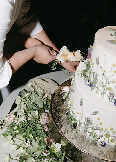 Couple cutting floral wedding cake at Hotel del Coronado, designed by Thater Made, a luxury wedding and event producer in San Diego, CA.