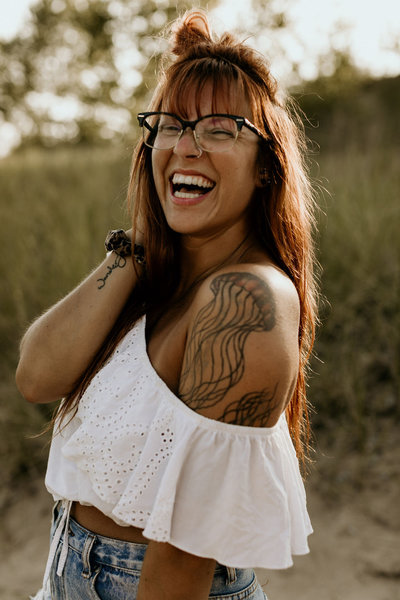 woman smiling with tattoos and glasses