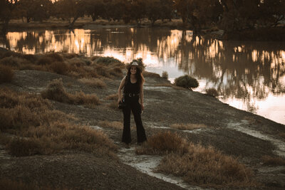 woman wearing a cowboy hat in a field holding a camera