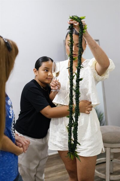 a small child hugging someone holding up a long lei 