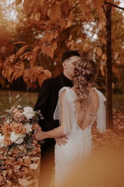 Bride with wavy braided wedding hair holding a bouquet of earth-toned flowers