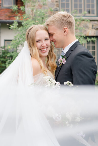 bride smiling at camera with groom smiling at bride photographed by northwest wedding photographer ashleigh grzybowski
