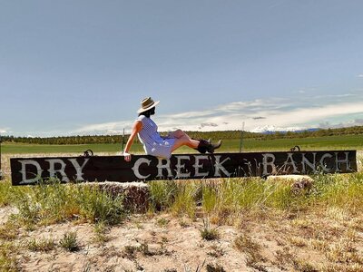 Author TJ Deal sit on Day Creek Ranch sign