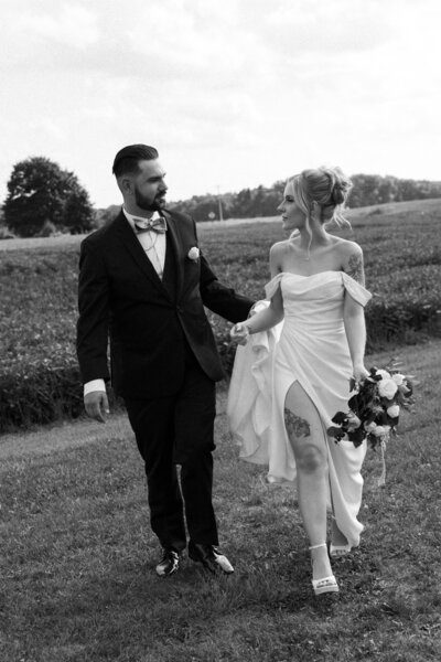 A couple in long sleeves and jackets stands closely together for a black and white portrait, framed by the peaceful woods around them.