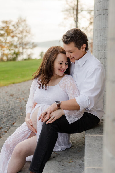 Couple sitting on steps at maternity shoot in Finger Lakes