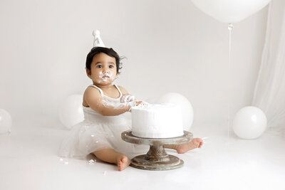 A baby smiles while laying on a white backdrop posed by a Vancouver Photographer