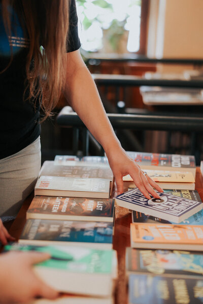People reach for books on a table