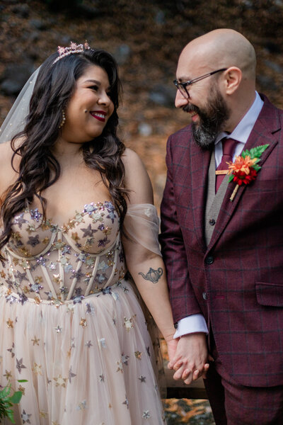 tattooed bride and groom hold hands and smile
