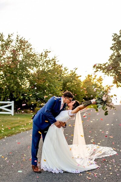 A bride and a groom are holding hands in front of an officiant underneath an archway.