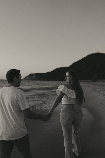 black and white photo of couples holding hands walking on the beach of Lake Michigan
