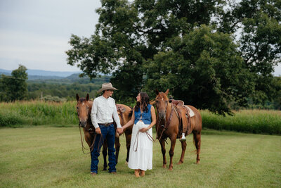 man and woman walking together leading their horses behind them
