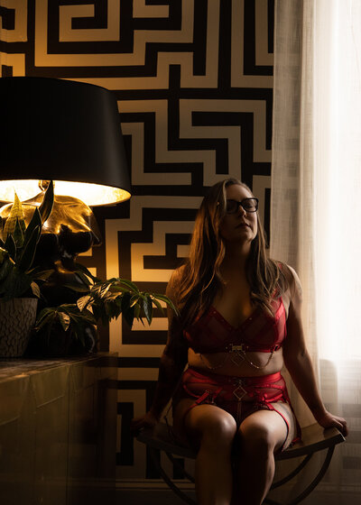 Woman seated in a bright studio surrounded by artful decor and soft lighting
