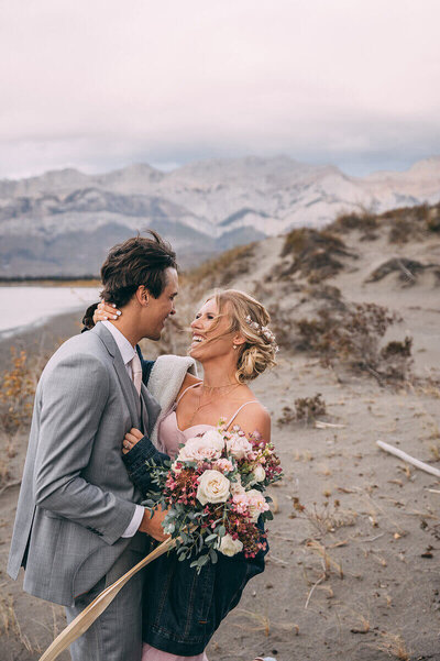 A wedding couple standing close together as they are about to kiss in the mountains.