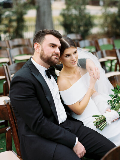 Bride and groom sitting in chairs leaning against each other