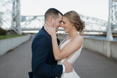 Newlyweds standing forehead to forehead as they smile at each other 