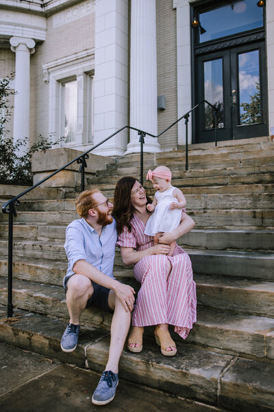 Family of three sitting on a staircase. 