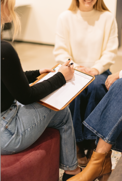 Female with brown straight hair posing at the camera with greenery in the background