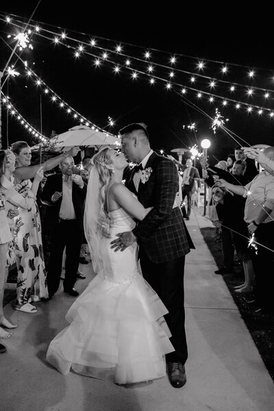 bride and groom share a kiss beneath sparklers from the crowd of guests