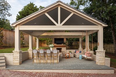 Custom covered outdoor living pavilion with a swing, fireplace, and bar seating, designed by Better Lawns and Gardens for a luxury backyard in Little Rock, Arkansas.