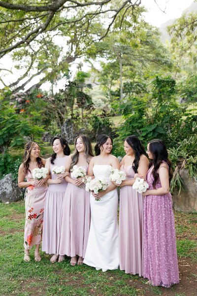 A newlywed smiling with their wedding party around them 