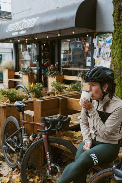 Woman cyclist drinking coffee at Velostar Cafe in Vancouver