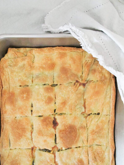 homemade spanakopita (greek spinach pie) in a large silver baking pan.