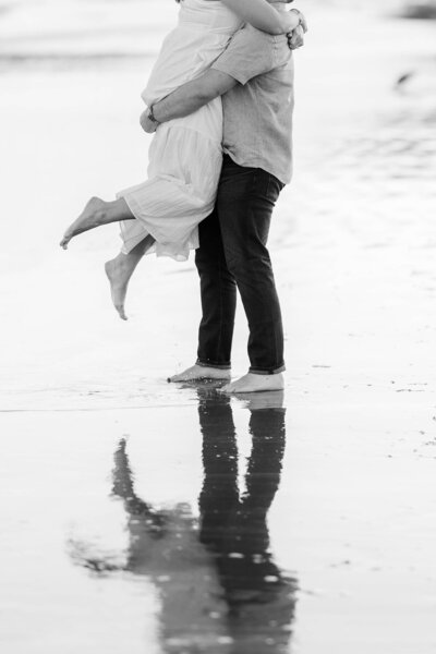 engaged couple posing with woman's hands around man's neck showcasing pearl engagement ring