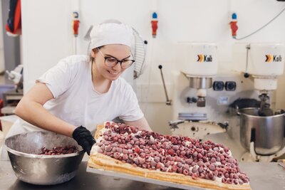 Konditorlehrling Barbara gibt Himbeeren auf unseren Himbeerstrudel