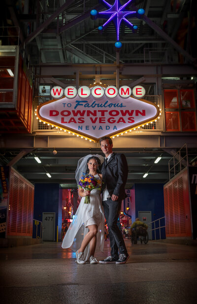 Famous Fremont street welcome to fabulous las vegas sign bride in short white wedding dress groom in jeans and jacket mk delacy photography las vegas wedding photographers