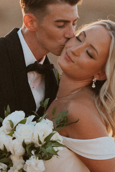 a bride and groom showing affection on their wedding day with their photographer in los angeles california
