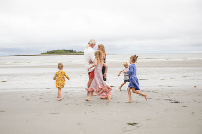 Kids running around two adults on beach | Family Photos