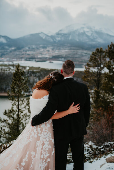 Newlyweds cuddle and look out into the mountains after their Elopement in Dillion, Colorado