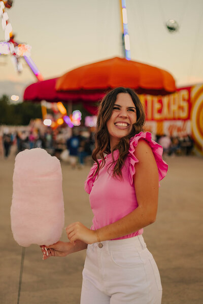 girl posing with cotton candy for senior photos in dallas
