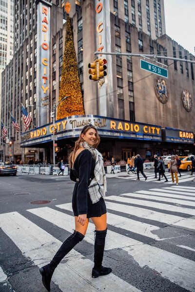 Girl walking across street new Radio City building while smiling over her shoulder at the camera
