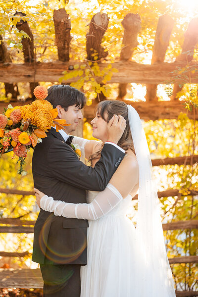 gorgeous fall sunlight falls on wedding portraits adorned with autumn toned florals