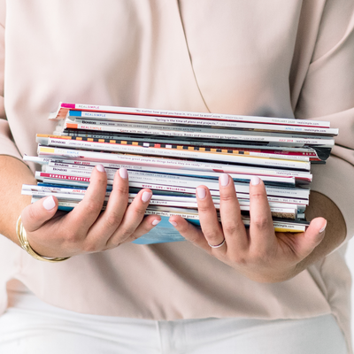 women holding stack of magazines