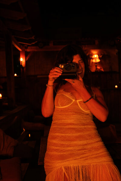Tristan Thibodeau holding a camera, bathed in amber light, embracing the wild feminine.