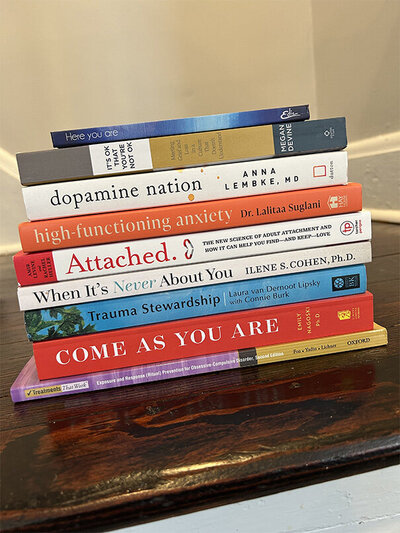 A stack of colorful books resting on a rustic wooden table.