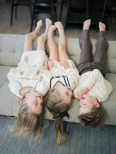Siblings having fun on a sofa during an in-home photoshoot in Vancouver, BC