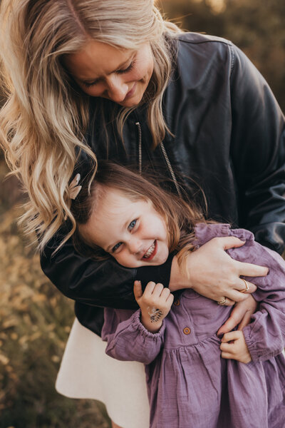 Golden hour family session with mother holding baby sitting on log