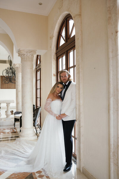 married couple leaning against a wall looking at the camera