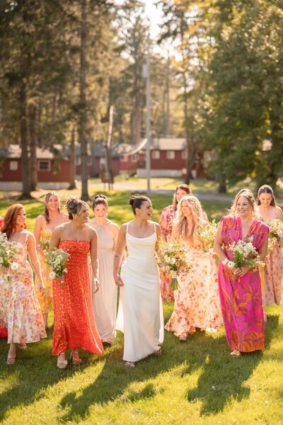 Bride and her bridesmaids in colorful dresses walking outside in the bright sun