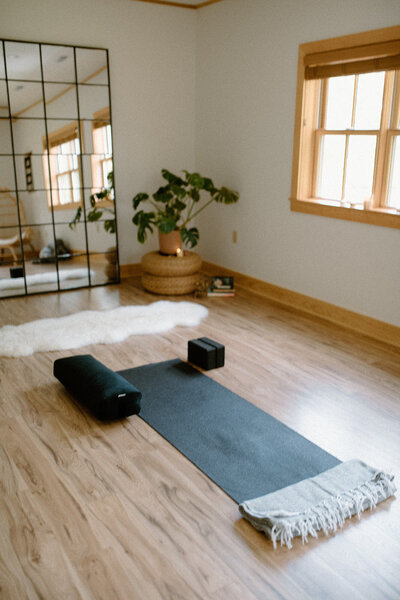 Studio space at Alyn Wellness Studio with a yoga mat and large mirror against the wall