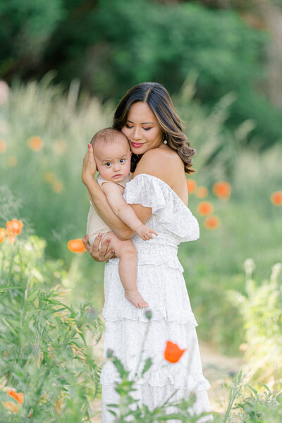 mother holding baby in flower field