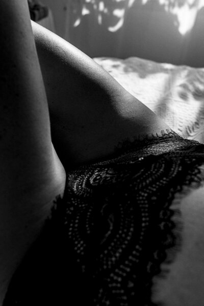 gros plan du bas ventre et jambes d'un femme en culotte en dentelle noir avec des jeux d'ombres