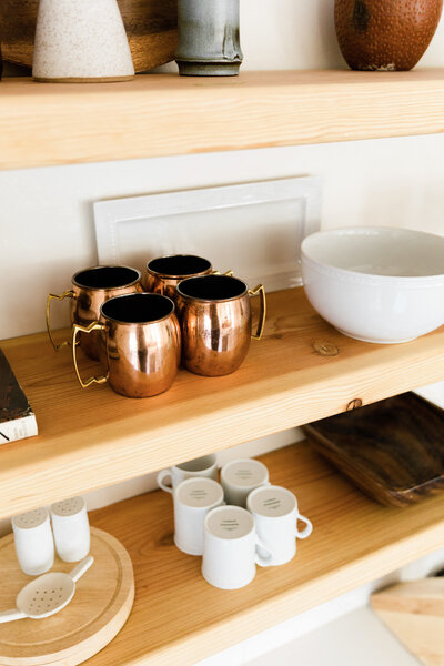 natural wood kitchen shelves with copper mugs and neutral kitchenware