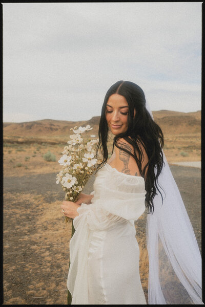 Cinematic wedding photographer standing in the desert with flowers