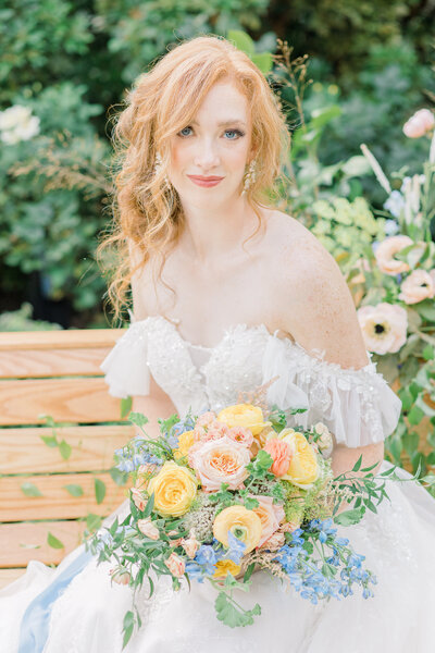 Portrait of bride in an off-the-shoulder lacy dress and holding a pastel colored bouquet