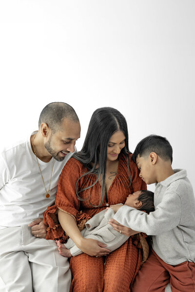 Lifestyle newborn photography session with two moms holding baby in cozy nursery with natural light— captured by Alliston and Barrie maternity, newborn, and family photographer.