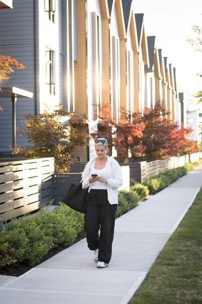 Amy walking down a street in Grandview looking at her phone